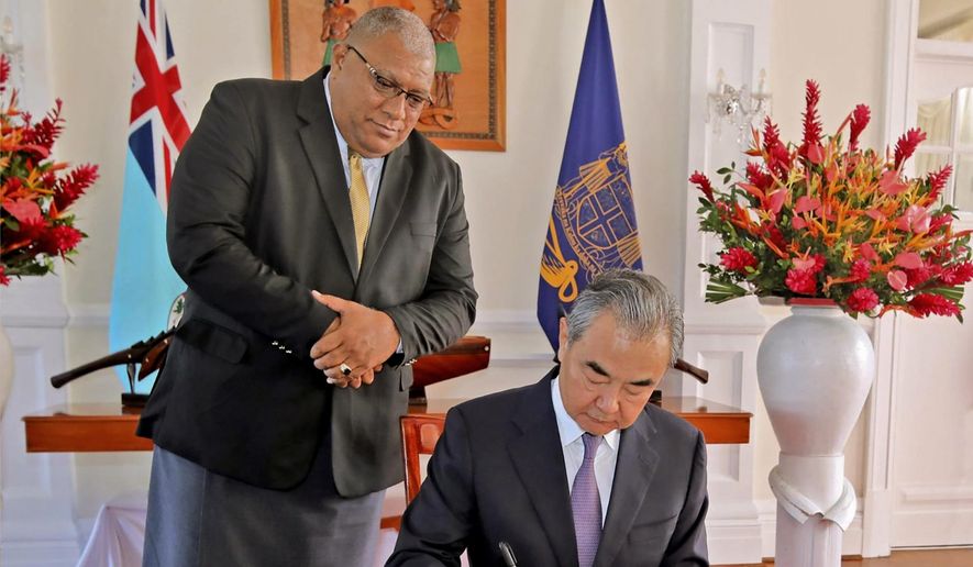 In this photo supplied by the Fiji government, the President of Fiji, Ratu Wiliame Katonivere, left, watches as the Chinese Foreign Minister Wang Yi signs the visitors book at the State House in Suva, Fiji, Monday, May 30, 2022. Wang and a 20-strong delegation are in Fiji as part of an eight-nation Pacific Islands tour that comes amid growing concerns about Beijing&#39;s military and financial ambitions in the South Pacific region. (Fiji Government via AP)