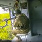In this handout photo released by the Russian Defense Ministry Press Service released on Saturday, May 28, 2022, Russian soldiers control the situation sitting on a board of a Mi-8 helicopter of the Russian air force during a mission at an undisclosed location in Ukraine. (Russian Defense Ministry Press Service via AP)