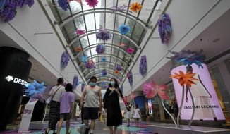 Residents wearing face masks walk through the reopening shopping mall decorated with colorful flowers after being closed due to COVID-19 restrictions in Beijing, Sunday, May 29, 2022. (AP Photo/Andy Wong)
