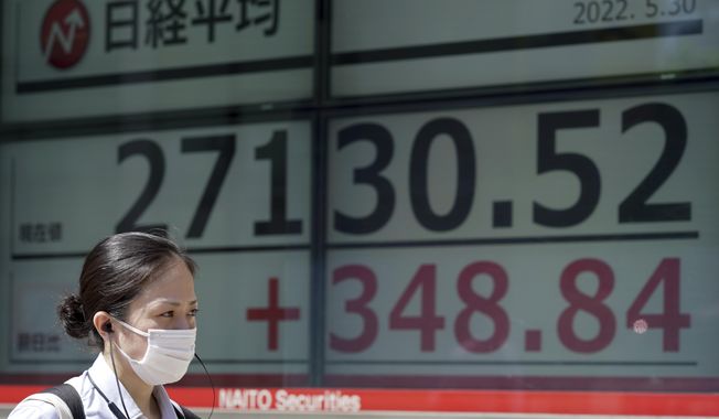A woman wearing a protective mask walks in front of an electronic stock board showing Japan&#x27;s Nikkei 225 index at a securities firm Monday, May 30, 2022, in Tokyo. Asian stocks rose Monday after Wall Street rebounded from a seven-week string of declines and China eased anti-virus curbs on business activity in Shanghai and Beijing. (AP Photo/Eugene Hoshiko)