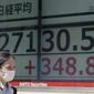 A woman wearing a protective mask walks in front of an electronic stock board showing Japan&#39;s Nikkei 225 index at a securities firm Monday, May 30, 2022, in Tokyo. Asian stocks rose Monday after Wall Street rebounded from a seven-week string of declines and China eased anti-virus curbs on business activity in Shanghai and Beijing. (AP Photo/Eugene Hoshiko)