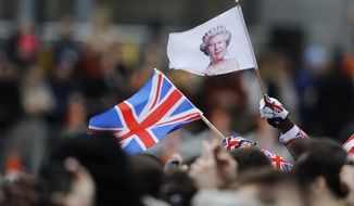 A man waves a British union flag and a flag bearing the image of Britain&#39;s Queen Elizabeth II ahead of the annual Commonwealth Day service at Westminster Abbey in London, Monday, March 9, 2020. After seven decades on the throne, Queen Elizabeth II is widely viewed in the U.K. as a rock in turbulent times. But in Britain’s former colonies, many see her as an anchor to an imperial past whose damage still lingers. (AP Photo/Frank Augstein, File)