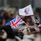 A man waves a British union flag and a flag bearing the image of Britain&#39;s Queen Elizabeth II ahead of the annual Commonwealth Day service at Westminster Abbey in London, Monday, March 9, 2020. After seven decades on the throne, Queen Elizabeth II is widely viewed in the U.K. as a rock in turbulent times. But in Britain’s former colonies, many see her as an anchor to an imperial past whose damage still lingers. (AP Photo/Frank Augstein, File)