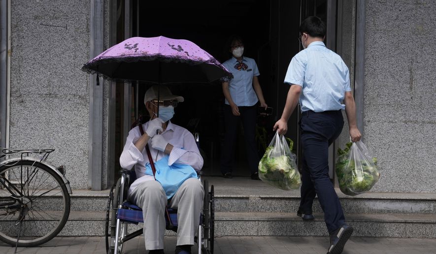 An elderly resident waits outside a bank as bank workers receive food supplies as banking services reopen after pandemic measure lockdown are lifted, Tuesday, May 31, 2022, in Beijing. (AP Photo/Ng Han Guan)