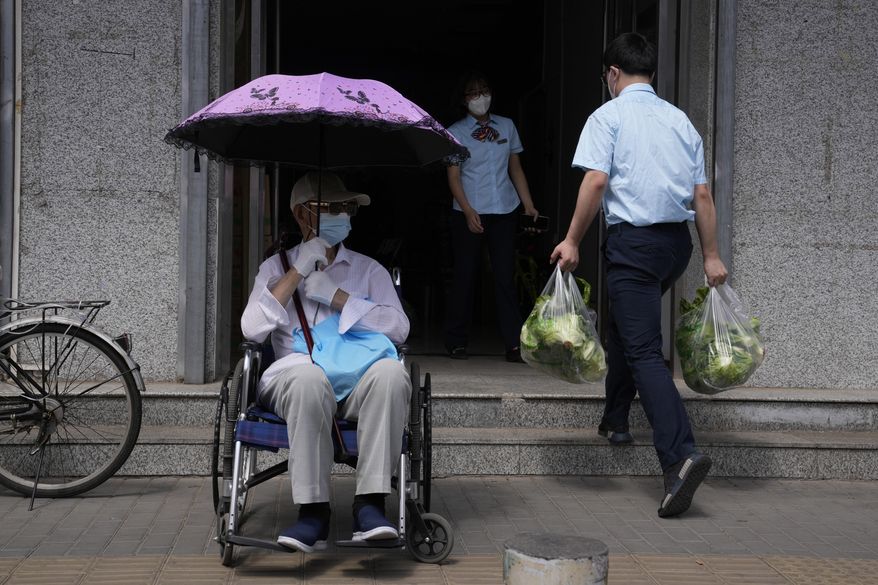 An elderly resident waits outside a bank as bank workers receive food supplies as banking services reopen after pandemic measure lockdown are lifted, Tuesday, May 31, 2022, in Beijing. (AP Photo/Ng Han Guan)