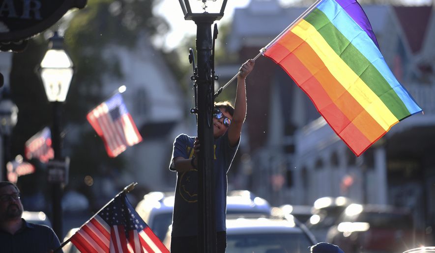 Families took part in the changing of the downtown Nevada City flags along Broad Street, Commercial Street, and Union Alley where the Pride flag is displayed for the month of June and Pride month, Tuesday, May 31, 2022. (Elias Funez/The Union via AP)