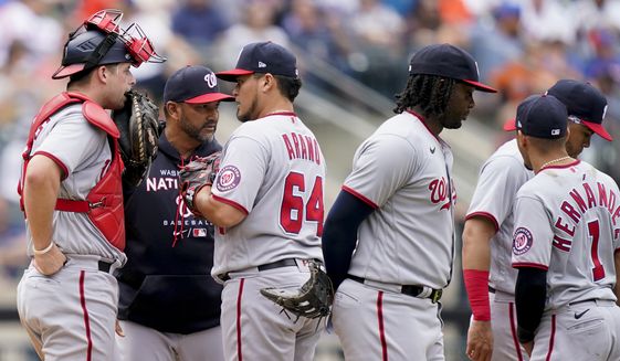 Washington Nationals manager Dave Martinez, second from left, hands the ball to relief pitcher Victor Arano (64) after relieving starting pitcher Evan Lee in the fourth inning of a baseball game against the New York Mets, Wednesday, June 1, 2022, in New York. (AP Photo/John Minchillo)