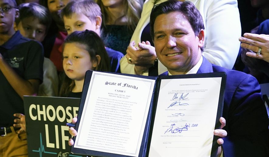 Florida Gov. Ron DeSantis holds up a 15-week abortion ban law after signing it on April 14, 2022, in Kissimmee, Fla. Reproductive health providers sued Florida on Wednesday, June 1, 2022, alleging that the law violates a provision in the state constitution guaranteeing a person’s right to privacy, “including the right to abortion.” (AP Photo/John Raoux, File)  **FILE**
