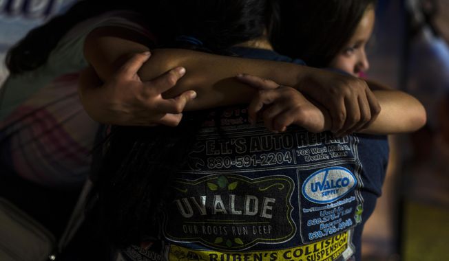 A mother and her two daughters embrace one another while visiting a memorial at a town square in Uvalde, Texas, Tuesday, May 31, 2022, to pay their respects to the victims killed in last week&#x27;s elementary school shooting. (AP Photo/Jae C. Hong)
