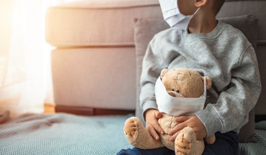Child and his teddy bear both in protective medical masks sit on windowsill, looking out a window.  Photo credit: Dragana Gordic via Shutterstock