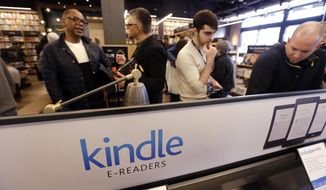 Customers stand near a display of Kindle electronic readers at the opening day for Amazon Books, the first brick-and-mortar retail store for online retail giant Amazon, Nov. 3, 2015, in Seattle. Amazon said Thursday, June 2, 2022 it will shut down its digital Kindle bookstores in China and stop selling the device to retailers in the country. The company said in a WeChat post that the bookstore will stop operating on June 30, 2023. (AP Photo/Elaine Thompson)