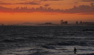 FILE - A man wades into the ocean at sunset on June 22, 2021, in Newport Beach, Calif. The National Oceanic and Atmospheric Administration announced Friday, June 3, 2022, that the amount of carbon dioxide in the atmosphere in May averaged 421 parts per million, more than 50% higher than pre-industrial levels. The NOAA said carbon dioxide levels in the air in May have reached a point last known when Earth was 7 degrees hotter, millions of years ago. (AP Photo/Jae C. Hong, File)