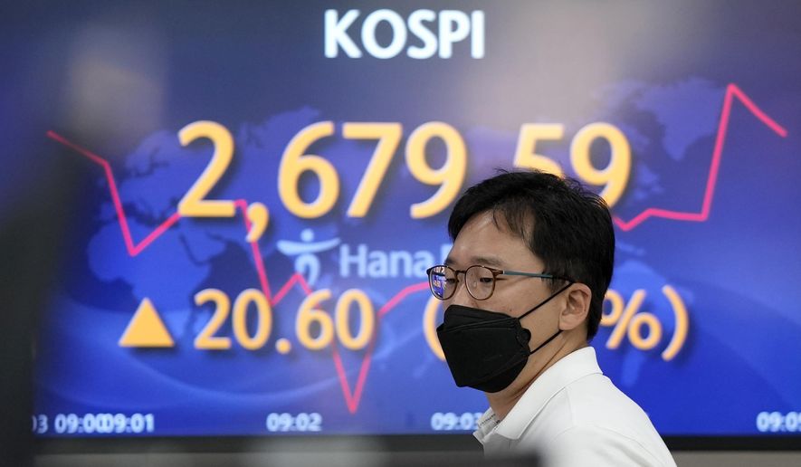 A currency trader walks by the screens showing the Korea Composite Stock Price Index (KOSPI) at a foreign exchange dealing room in Seoul, South Korea, Friday, June 3, 2022. Asian shares rose Friday amid mixed signs for investors such as rising energy prices and COVID-19 restrictions easing in China. (AP Photo/Lee Jin-man)