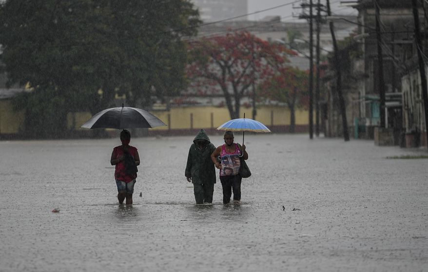 Residents wade through a street flooded by heavy rains, in Havana, Cuba, Friday, June 3, 2022. Heavy rains have drenched Cuba with almost non-stop rain for the last 24 hours as tropical storm watches were posted Thursday for Florida, Cuba and the Bahamas as the system that battered Mexico moves to the east. (AP Photo/Ramon Espinosa)