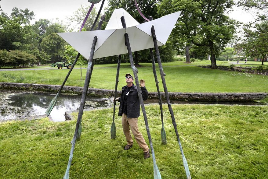 Santa Fe, New Mexico sculpture artist Kevin Box watches as his piece titled "Light Boat" is lowered to the ground near the spring house at the Museum of the Shenandoah Valley in Winchester, Virginia on May 25, 2022 for the Origami in the Garden exhibit. (Jeff Taylor/The Winchester Star via AP)