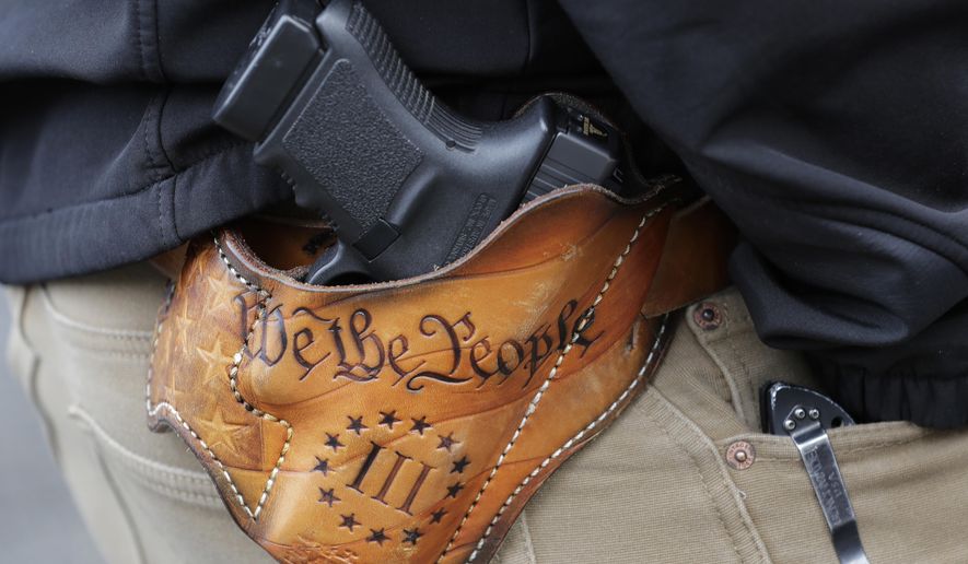 An attendee at a gun rights rally open carries his gun in a holster that reads &amp;quot;We the People&amp;quot; from the Preamble to the United States Constitution, Friday, Jan. 18, 2019, at the Capitol in Olympia, Wash. (AP Photo/Ted S. Warren, File)