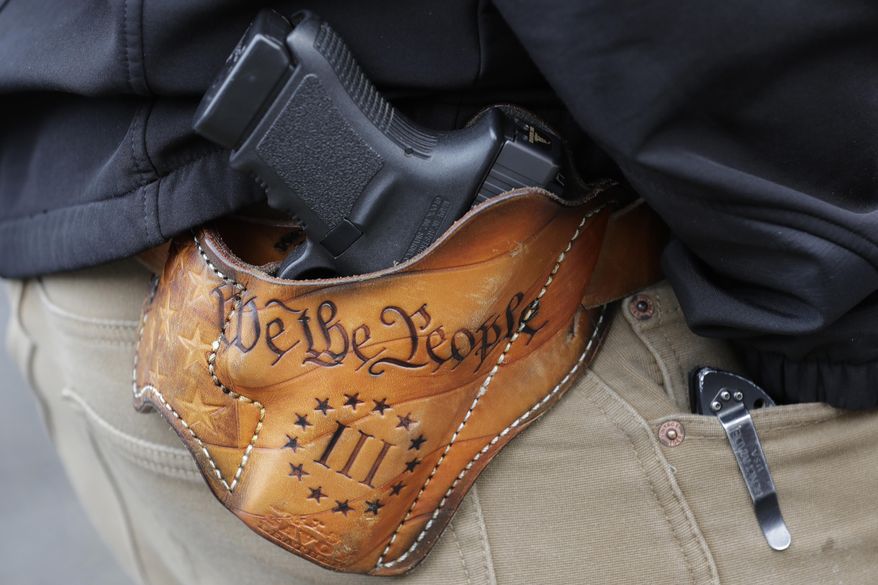 An attendee at a gun rights rally open carries his gun in a holster that reads "We the People" from the Preamble to the United States Constitution, Friday, Jan. 18, 2019, at the Capitol in Olympia, Wash. (AP Photo/Ted S. Warren, File)