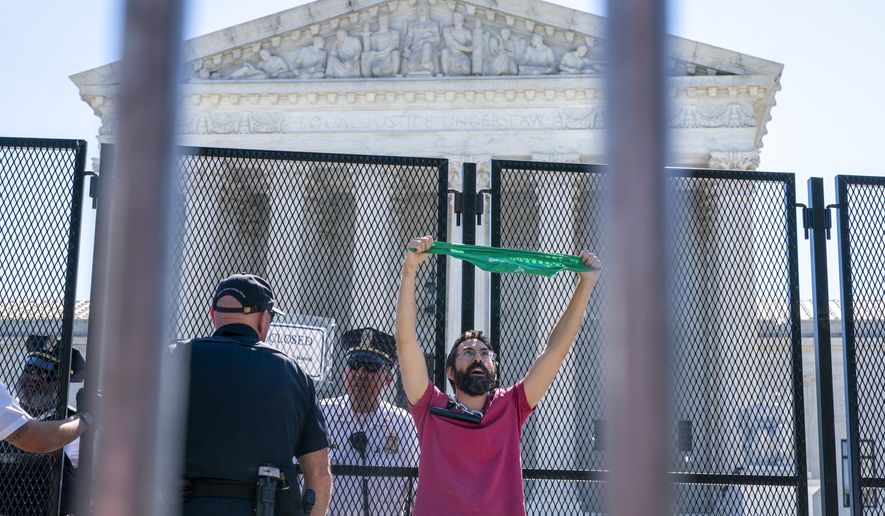 An abortion rights demonstrator chains himself by the neck to an anti-scaling fence as he protests Monday, June 6, 2022, outside the Supreme Court in Washington. (AP Photo/Jacquelyn Martin) **FILE**