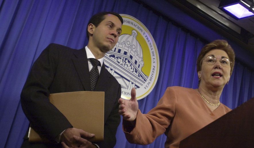 Dominican Secretary for Commerce and Industry Sonia Guzman, right, talks to the media accompanied by Orlando Jorge Mera, at the presidential palace in Santo Domingo, Dominican Republic, March 16, 2004. Mera, the Dominican Republic’s minister of the environment and natural resources, was shot and killed in his office on Monday, June 6, 2022, according to officials. (AP Photo/Walter Astrada, File)
