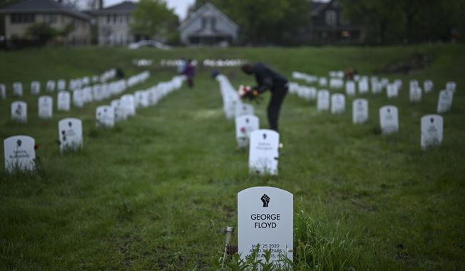 Community members lay flowers down near gravestone markers at the &#x27;Say Their Names&#x27; cemetery Wednesday, May 25, 2022, in Minneapolis. The intersection where George Floyd died at the hands of Minneapolis police officers was renamed in his honor Wednesday, among a series of events to remember a man whose killing forced America to confront racial injustice. (Aaron Lavinsky/Star Tribune via AP)
