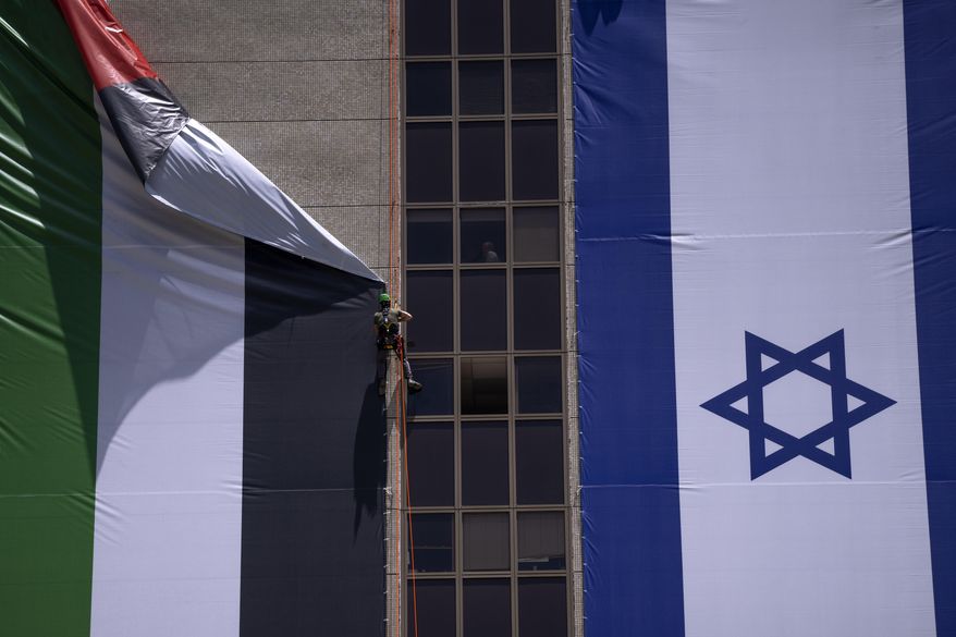 A Palestinian flag is removed from a building by Israeli authorities after being put up by an advocacy group that promotes coexistence between Palestinians and Israelis, in Ramat Gan, Israel, Wednesday, June 1, 2022. In recent weeks, Israeli authorities have gone out of their way to challenge the hoisting of the Palestinian flag. Palestinian citizens of Israel see the campaign against the flag as another affront to their national identity and their rights as a minority in the majority Jewish state. (AP Photo/Oded Balilty, File)