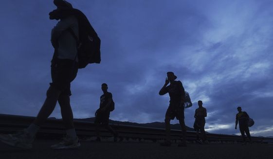 Migrants walk north on the highway toward the exit to Huixtla, Chiapas state, Mexico, at sunrise Thursday, June 9, 2022. The group left Tapachula on Monday, tired of waiting to normalize their status in a region with little work. (AP Photo/Marco Ugarte)