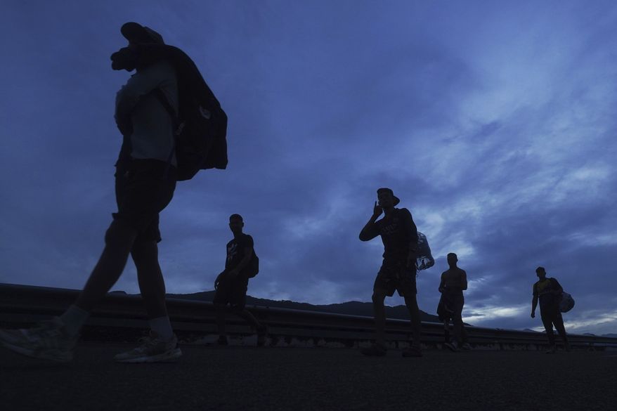 Migrants walk north on the highway toward the exit to Huixtla, Chiapas state, Mexico, at sunrise Thursday, June 9, 2022. The group left Tapachula on Monday, tired of waiting to normalize their status in a region with little work. (AP Photo/Marco Ugarte)