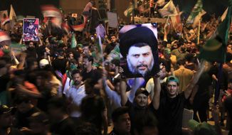 Followers of Shiite cleric Muqtada al-Sadr, on the poster, celebrate after the announcement of the results of the parliamentary elections in Tahrir Square, Baghdad, Iraq, Monday, Oct. 11, 2021. Eight months after national elections, Iraq still doesn&#39;t have a government. Driven by cutthroat competition for power and resources between elites, there is no clear way out of the unprecedented impasse. (AP Photo/Hadi Mizban, File)
