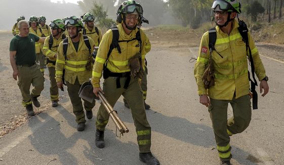 Firefigters walk in the area of a wildfire in Pujerra, Malaga, on Thursday, June 9, 2022. Emergency services deployed almost 1,000 firefighters, military personnel and support crews Thursday to fight a wildfire that has forced the evacuation of some 2,000 people in southern Spain amid fears that torrid weather may feed the blaze. (Alex Zea, Europa Press via AP)