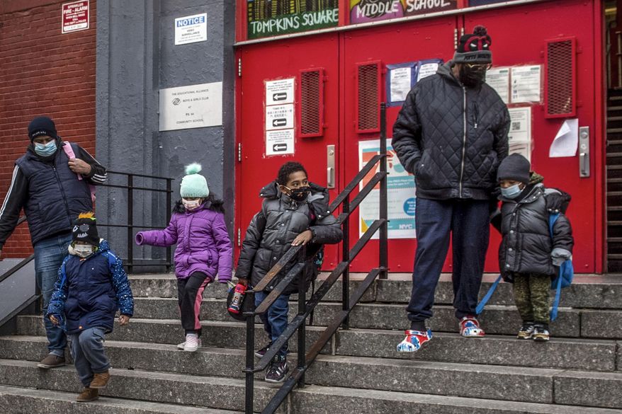 Children and their guardians wearing masks because of COVID-19 pandemic, leave P.S. 64 in the East Village neighborhood of Manhattan, Dec. 21, 2021, in New York. New York City will end its mask mandates for children under 5 on Monday, June 13, 2022, as the threat from COVID infections further subside. (AP Photo/Brittainy Newman, File) **FILE**