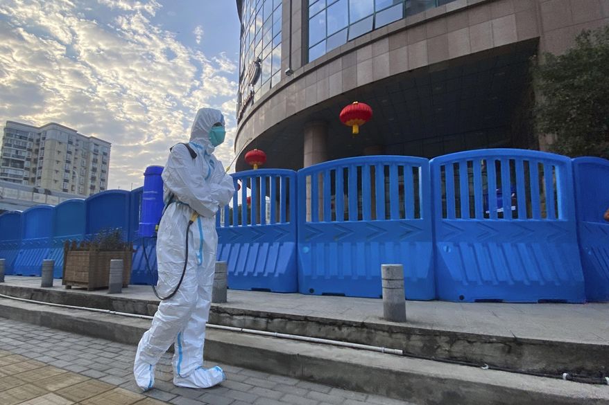 A worker in protectively overalls and carrying disinfecting equipment walks outside the Wuhan Central Hospital, China on  Feb. 6, 2021. Experts drafted by the World Health Organization to help investigate the origins of the coronavirus pandemic say further research is needed to determine how COVID-19 first began. They say they need a more detailed analysis of the possibility it was a laboratory accident. (AP Photo/Ng Han Guan, File)