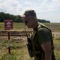 A Ukrainian soldier walks near a post warning about landmines in a field on the outskirts of Kyiv, Ukraine, Thursday, June 9, 2022. (AP Photo/Natacha Pisarenko) ** FILE **