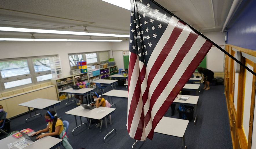 An American flag is in a classroom as students work on laptops in Newlon Elementary School early Tuesday, Aug. 25, 2020, which is one of 55 Discovery Link sites set up by Denver Public Schools where students are participating in remote learning in this time of the new coronavirus from a school in Denver. (AP Photo/David Zalubowski)