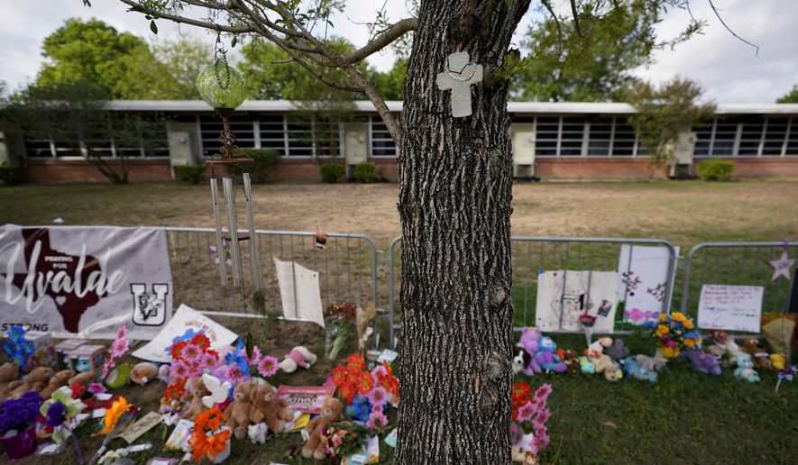 FILE - A cross hangs on a tree at Robb Elementary School on June 3, 2022, in Uvalde, Texas, where a memorial has been created to honor the victims killed in the recent school shooting. Two teachers and 19 students were killed. As public pressure mounts for more information on the deadly Uvalde school shooting, some are concerned that Texas officials will use a legal loophole to block records from being released — even to the victims&#39; families — once the case is closed.(AP Photo/Eric Gay, File)
