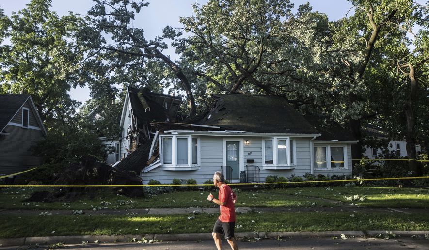 A person jogs past a large tree that fell into the roof of a home in Riverside during Monday evening&#39;s storm that raced across the Chicago area.  A supercell thunderstorm with winds in excess of 80 mph (129 kph) toppled trees and damaged power lines Monday evening as it left a trail of damage across the Chicago area and into northwestern Indiana, the National Weather Service said.   (Steven Rosenberg/Chicago Tribune via AP)