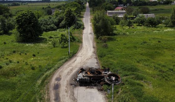 A ruined tank remains on a road in Lypivka, on the outskirts of Kyiv, Ukraine, Tuesday, June 14, 2022. Russia’s invasion of Ukraine is spreading a deadly litter of mines, bombs and other explosive devices that will endanger civilian lives and limbs long after the fighting stops. (AP Photo/Natacha Pisarenko)