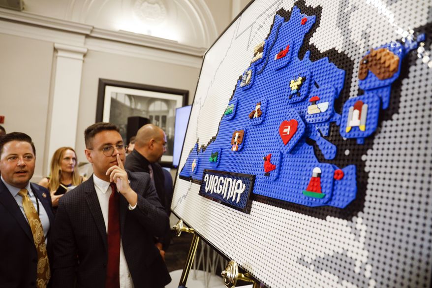 People try to guess the landmarks on a map of Virginia made of Lego blocks at a news conference at the Science Museum of Virginia, Wednesday, June 15, 2022 in Richmond, Va., The Danish toy company said Wednesday it plans to invest more than $1 billion over 10 years to build a new factory in Virginia and to enlarge an existing factory in Mexico. (Shaban Athuman/Richmond Times-Dispatch via AP)