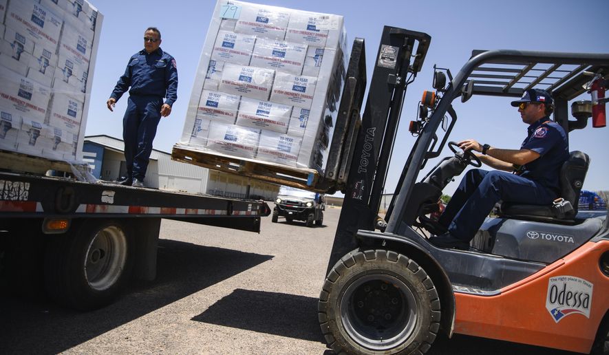 Odessa Fire Rescue Chief John Alvarez, left, and Central Station Captain Austin Yocham unload pallets of emergency drinking water as they help prepare to hand out cases of water for residents in need after a broken water main left the majority of Ector County without clean running water Tuesday, June 14, 2022 in Odessa, Texas. (Eli Hartman/Odessa American via AP)
