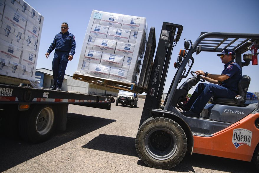 Odessa Fire Rescue Chief John Alvarez, left, and Central Station Captain Austin Yocham unload pallets of emergency drinking water as they help prepare to hand out cases of water for residents in need after a broken water main left the majority of Ector County without clean running water Tuesday, June 14, 2022 in Odessa, Texas. (Eli Hartman/Odessa American via AP)