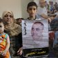 Amal el-Halabi holds her grandson Fares while her grandson Amro, 7, holds a picture of his father Mohammed el-Halabi, Gaza director of the international charity World Vision, who is detained and accused by Israeli security of diverting sums to Hamas that exceed its total budget, at his family house in Gaza City, Aug. 8, 2016. The Israeli district court in the southern Israeli city of Beersheba found Mohammed el-Halabi guilty of several terrorism charges on Wednesday, June 15, 2022. He has not yet been sentenced. Arabic on the picture reads, &amp;quot; the man of humanity.&amp;quot; (AP Photo/Adel Hana, File)