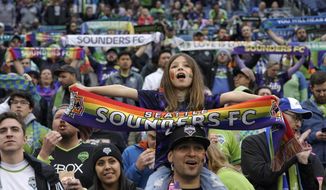 A young Seattle Sounders supporter holds a rainbow flag before an MLS soccer match between the Sounders and the Vancouver Whitecaps, Tuesday, June 14, 2022, in Seattle during Pride Month. (AP Photo/Ted S. Warren)