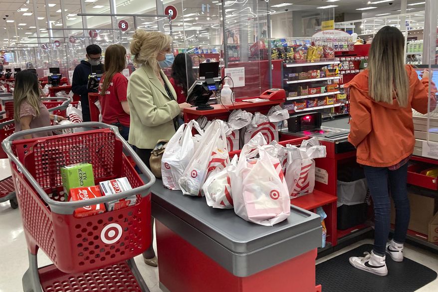 A customer wears a mask as she waits to get a receipt at a register in Target store in Vernon Hills, Ill., May 23, 2021. Americans cut their spending unexpectedly in May compared with the month before, underscoring how surging inflation on daily necessities like gas is causing them to be more cautious about buying discretionary items. (AP Photo/Nam Y. Huh, File)