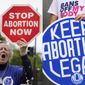 A woman holds a sign saying &amp;quot;stop abortion now,&amp;quot; at a protest outside of the U.S. Supreme Court in Washington on May 5, 2022, left, and another woman holds a sign during a news conference for reproductive rights in response to the leaked draft of the Supreme Court&#39;s opinion to overturn Roe v. Wade, in West Hollywood, Calif., on March 3, 2022. For families divided along red house-blue house lines, summer&#39;s slate of reunions, group trips and weddings poses another exhausting round of navigating divides. The season opens at a time of conflict fatigue. Pandemic restrictions have melted away but gun control, the fight for reproductive rights, the Jan. 6 insurrection hearings, the bite of high inflation and a range of other issues prevail. (AP Photo)