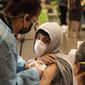 In this May 24, 2021, photo, a student looks back at his mother as he is vaccinated at a school-based COVID-19 vaccination clinic for students 12 and older in San Pedro, Calif. (AP Photo/Damian Dovarganes) **FILE**