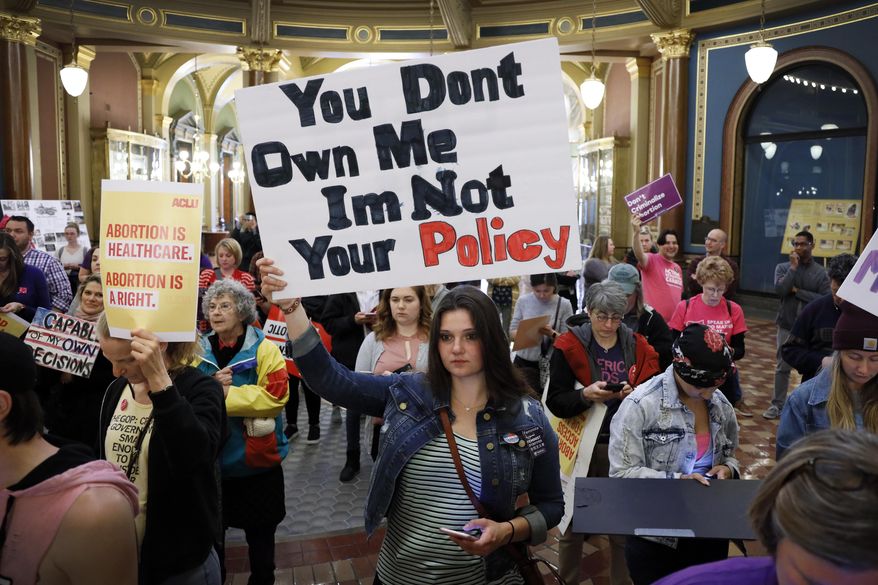 Marissa Messinger, of Lake View, Iowa, center, holds a sign during a rally to protest recent abortion bans, May 21, 2019, at the Statehouse in Des Moines, Iowa. The Iowa Supreme Court on Friday, June 17, 2022, cleared the way for lawmakers to severely limit or even ban abortion in the state, reversing a decision by the court just four years ago that guaranteed the right to the procedure under the Iowa Constitution. (AP Photo/Charlie Neibergall, File) **FILE**