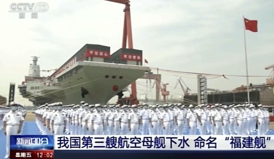 In this image taken from video footage run by China's CCTV, sailors line up in front of China's third aircraft carrier christened Fujian before its launching ceremony at a dry dock in Shanghai on Friday, June 17, 2022. State media reported that China on Friday launched its third aircraft carrier, the first such ship to be both designed and built entirely within the country. Chinese characters on screen reads "Our country's third aircraft carrier launched into water, named Fujian." (CCTV via AP)