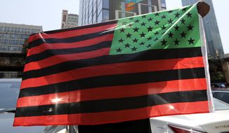 FILE - A man holds an African-American flag during a demonstration in Chicago on June 19, 2020, to mark Juneteenth, the holiday celebrating the day in 1865 that enslaved black people in Galveston, Texas, learned they had been freed from bondage, more than two years after the Emancipation Proclamation. Retailers and marketers from Walmart to Amazon have been quick to commemorate Juneteenth with an avalanche of merchandise from ice cream to T-shirts to party favors. (AP Photo/Nam Y. Huh, File)