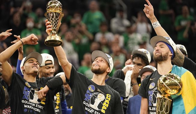 Golden State Warriors guard Stephen Curry, center, holds up the Bill Russell Trophy for most valuable player after the Warriors defeated the Boston Celtics in Game 6 to win basketball&#x27;s NBA Finals championship, Thursday, June 16, 2022, in Boston. (AP Photo/Steven Senne) **FILE**