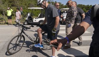 President Joe Biden gets back on his bike after falling when he tried to get off his bike at the end of a ride to greet a crowd at Gordons Pond in Rehoboth Beach, Del., Saturday, June 18, 2022. (AP Photo/Manuel Balce Ceneta)