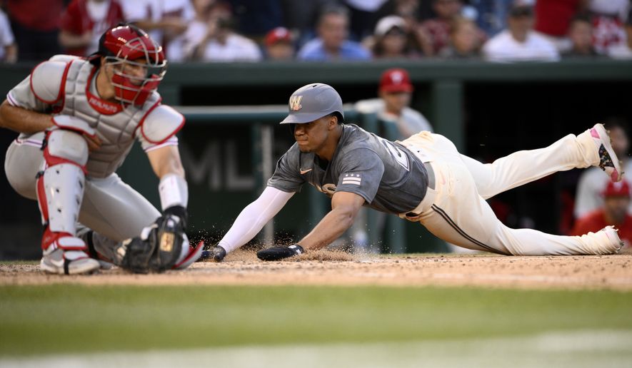 Washington Nationals&#x27; Juan Soto, right, slides home to score against Philadelphia Phillies catcher J.T. Realmuto, left, on a single by Lane Thomas during the ninth inning of a baseball game, Saturday, June 18, 2022, in Washington. (AP Photo/Nick Wass)